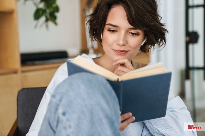 A woman enjoying a finance book, expanding her knowledge on money management and financial success strategies