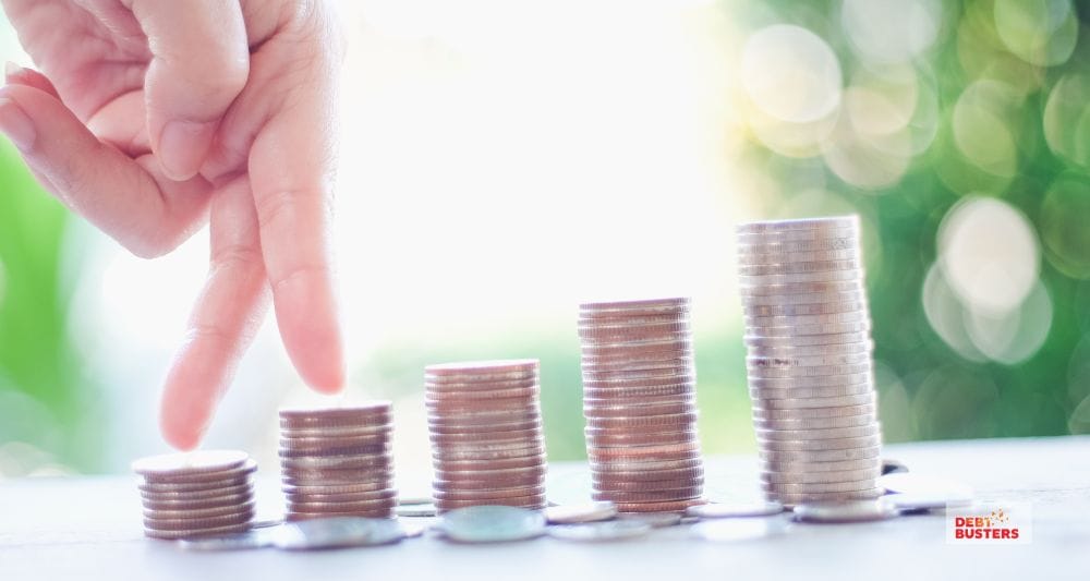Fingers climbing stacked coins, symbolising rising financial pressure from mortgage stress in Australia families.