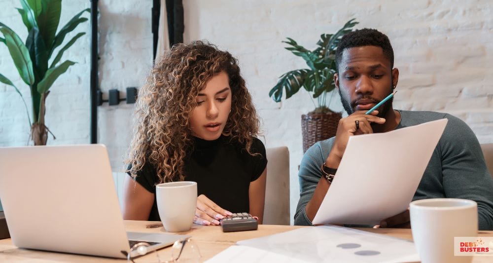 Couple reviewing finances and documents while exploring crisis loan for rent arrears eligibility.