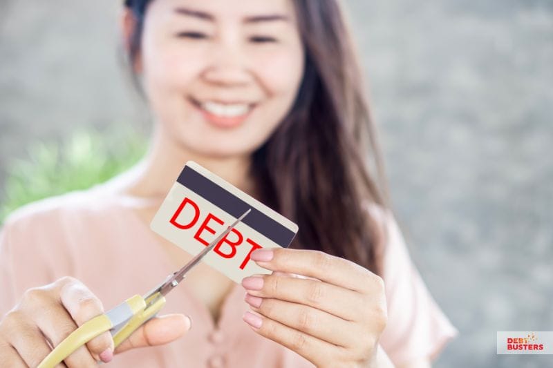 Woman cutting debt card symbolising relief after bankruptcy vs insolvency decisions